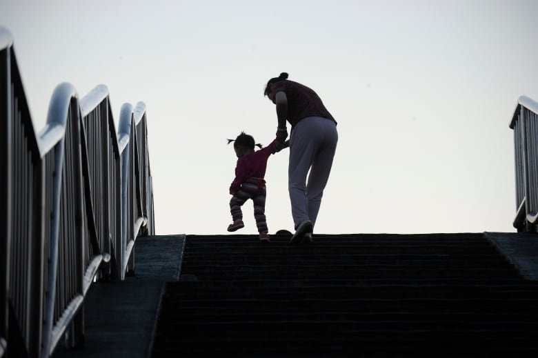 A family makes their way along the steps of a footbridge.