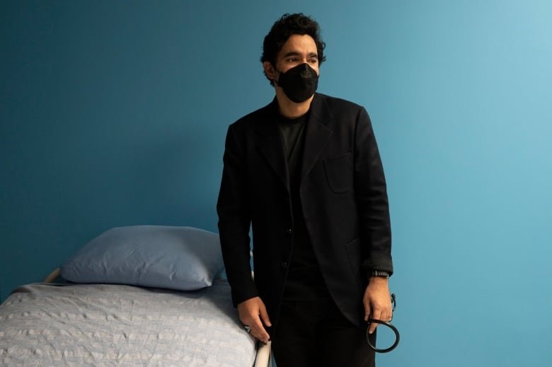 Dr. Andrew Boozary stands beside a hospital bed.