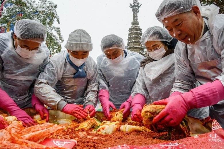 Participants prepare kimchi, a traditional Korean dish of spicy fermented cabbage and radish, during a kimchi making festival held amid snowfall at the Jogyesa Temple in Seoul.