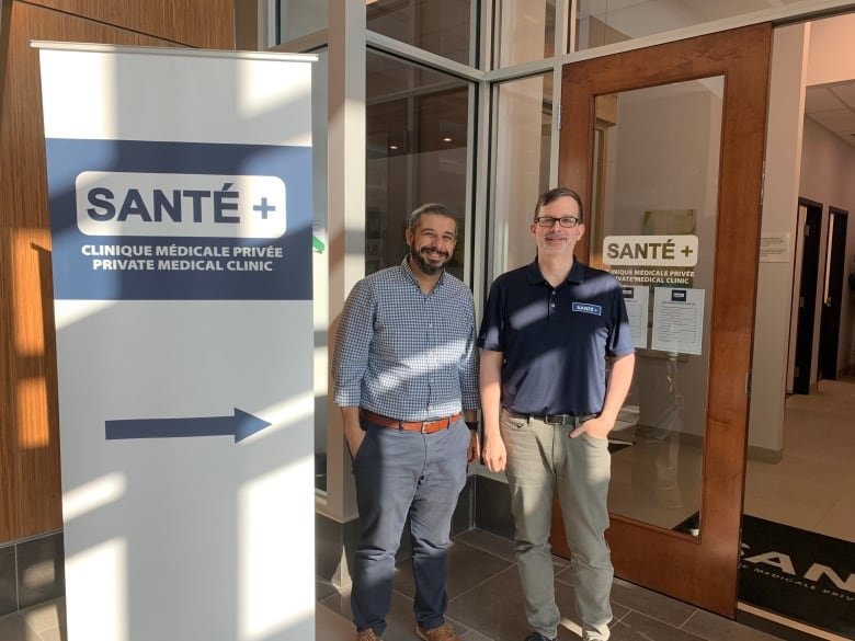 Two men pose for a photo in a lobby.