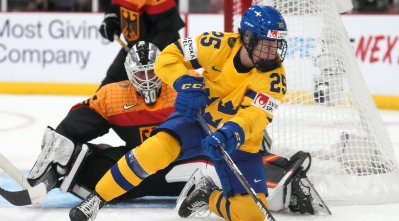 Women's hockey goaltender watches as a Swedish player handles the puck in front of her net.