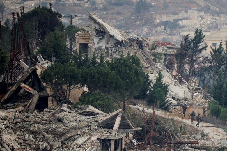 Soldiers stroll past a village.