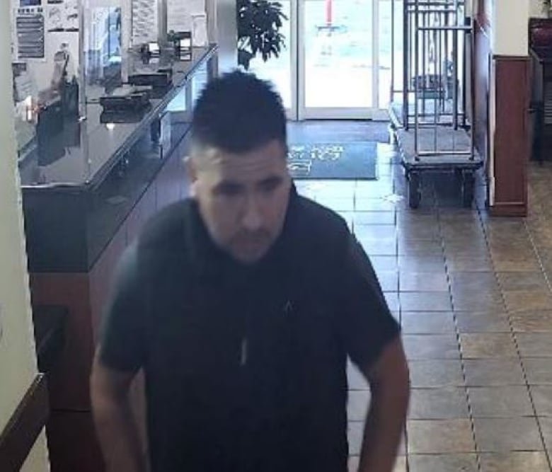 A still from surveillance footage shows a man with short, dark hair, wearing a short-sleeve top.