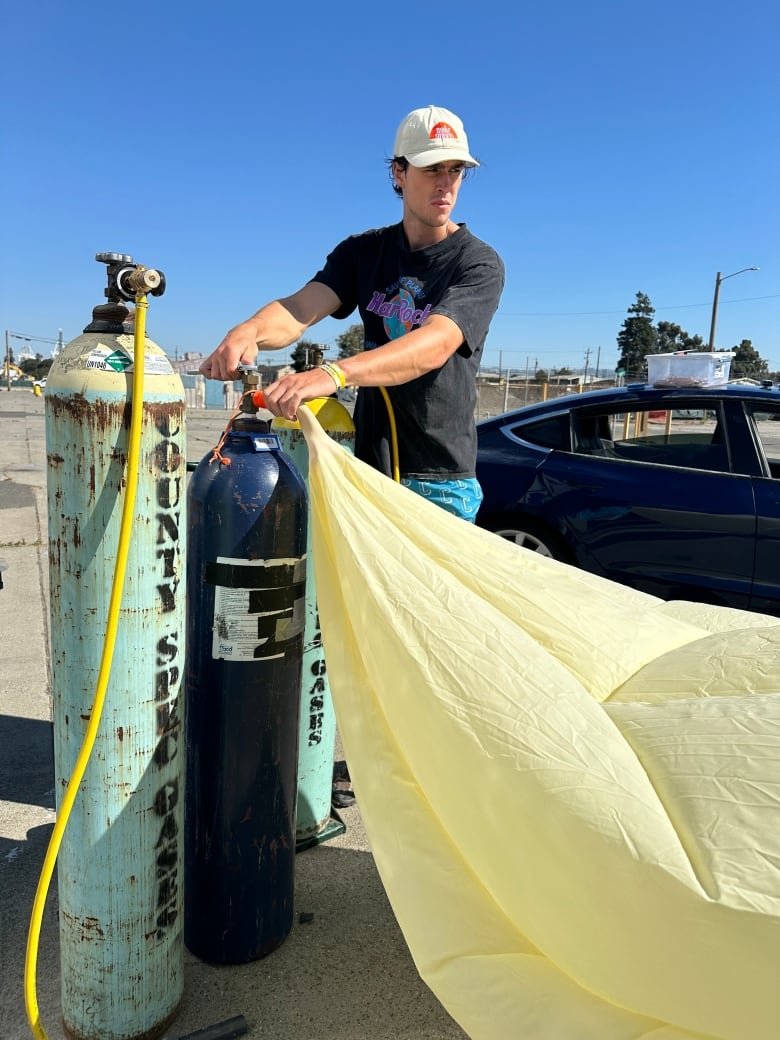 A man fills up a large balloon.