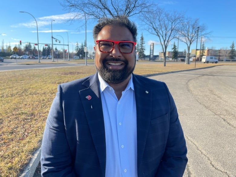 Man smiles with bright red glasses