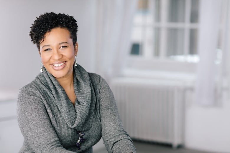 A woman in a grey sweater smiles for the camera.