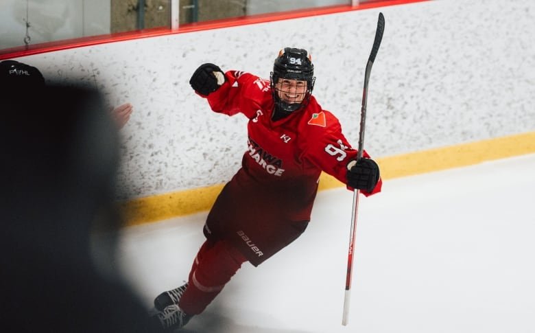 A female hockey player in a red Ottawa Charge jersey celebrates on the ice.