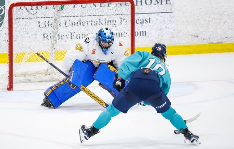 A female hockey player in a teal jersey with the number 10 and Fillier written on the back prepares to shoot the puck on a goaltender.