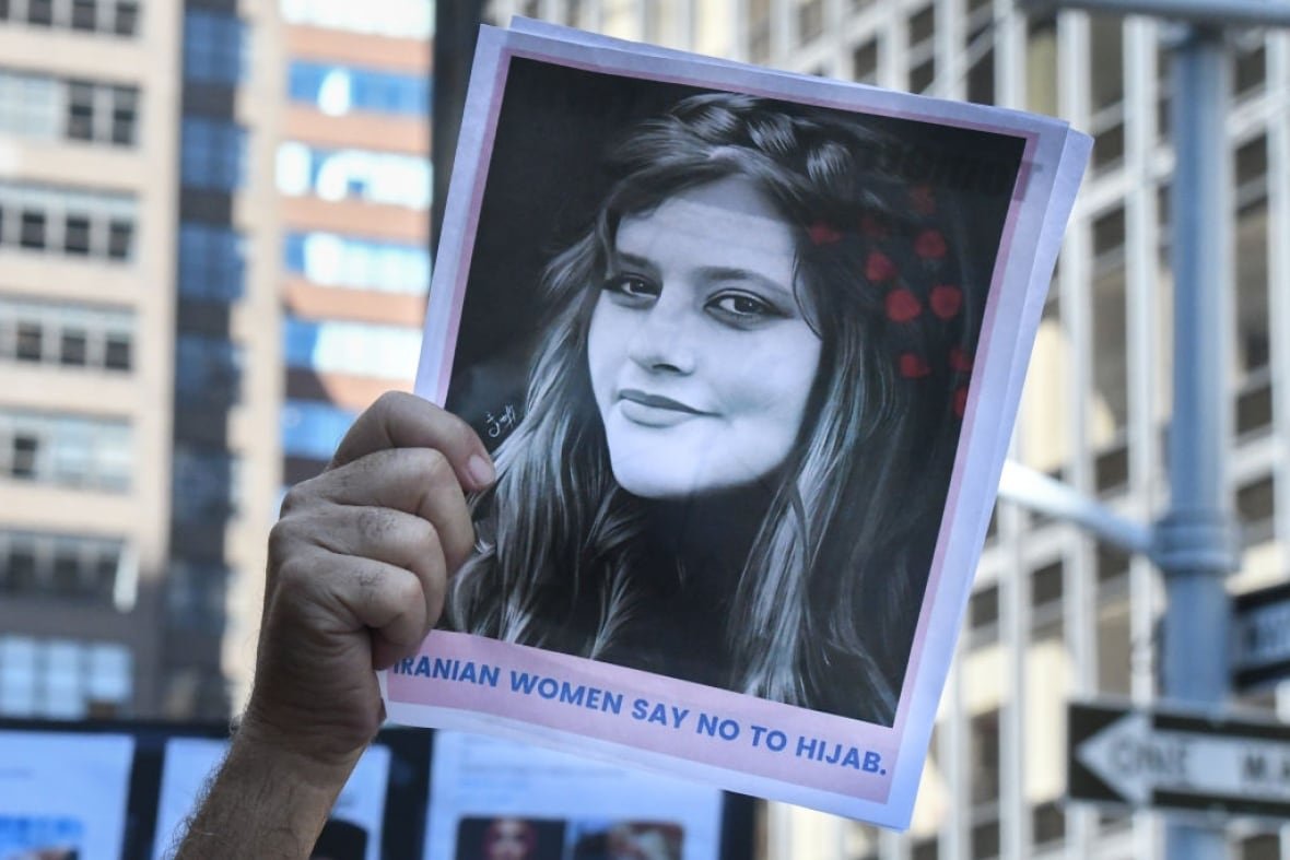 1243407628 An arm holds up a photo of an Iranian woman in a protest against Iranian President Ebrahim Raisi outside of the United Nations.