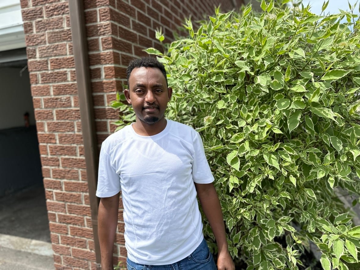 misghina-kidane man in white t-shirt in front of plant