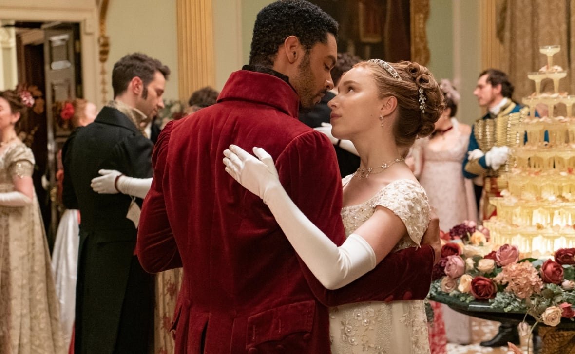 bridgerton A man and woman, dressed in 18th century formal wear, dance at a ball.
