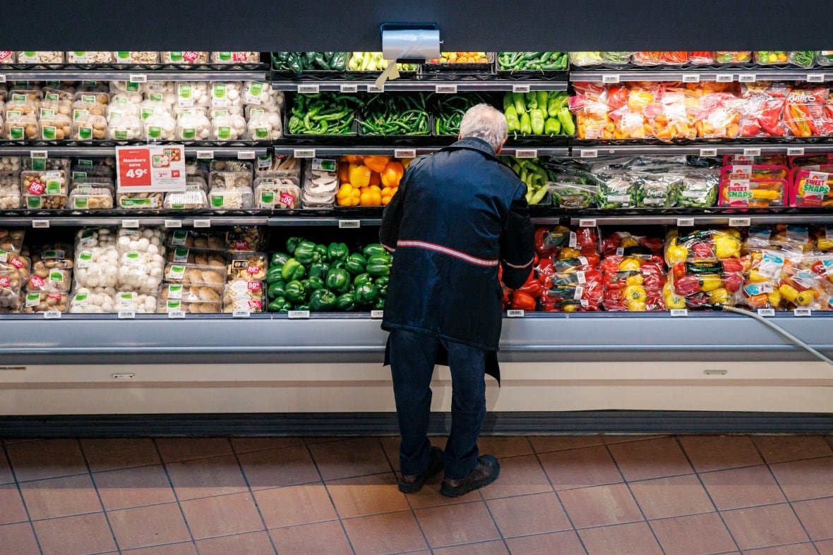 loblaws-buy-canadian-1 A man looks through the refrigerated vegetable section of a grocery store.