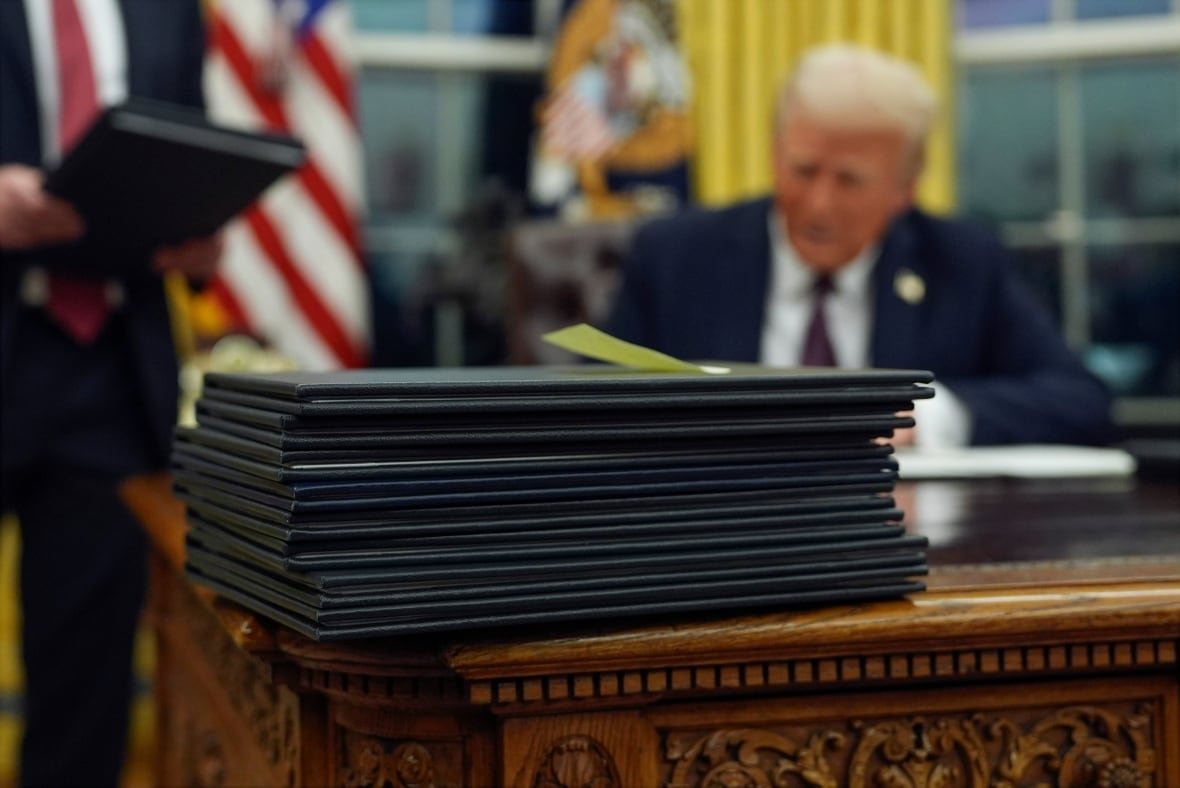 trump-inauguration-photo-gallery-1 A pile of documents in black folders are stacked on a wooden desk.