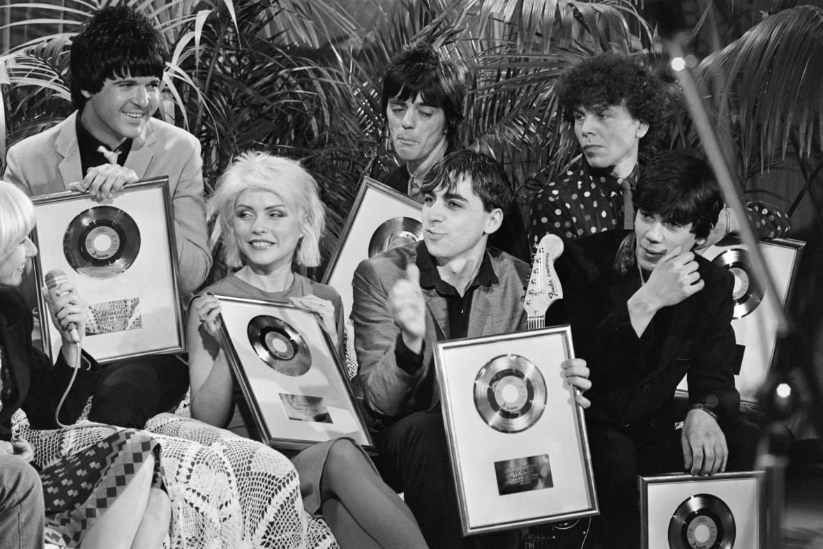 1242960670 Five men and one woman are shown seated and holding up framed records in a black and white photograph.