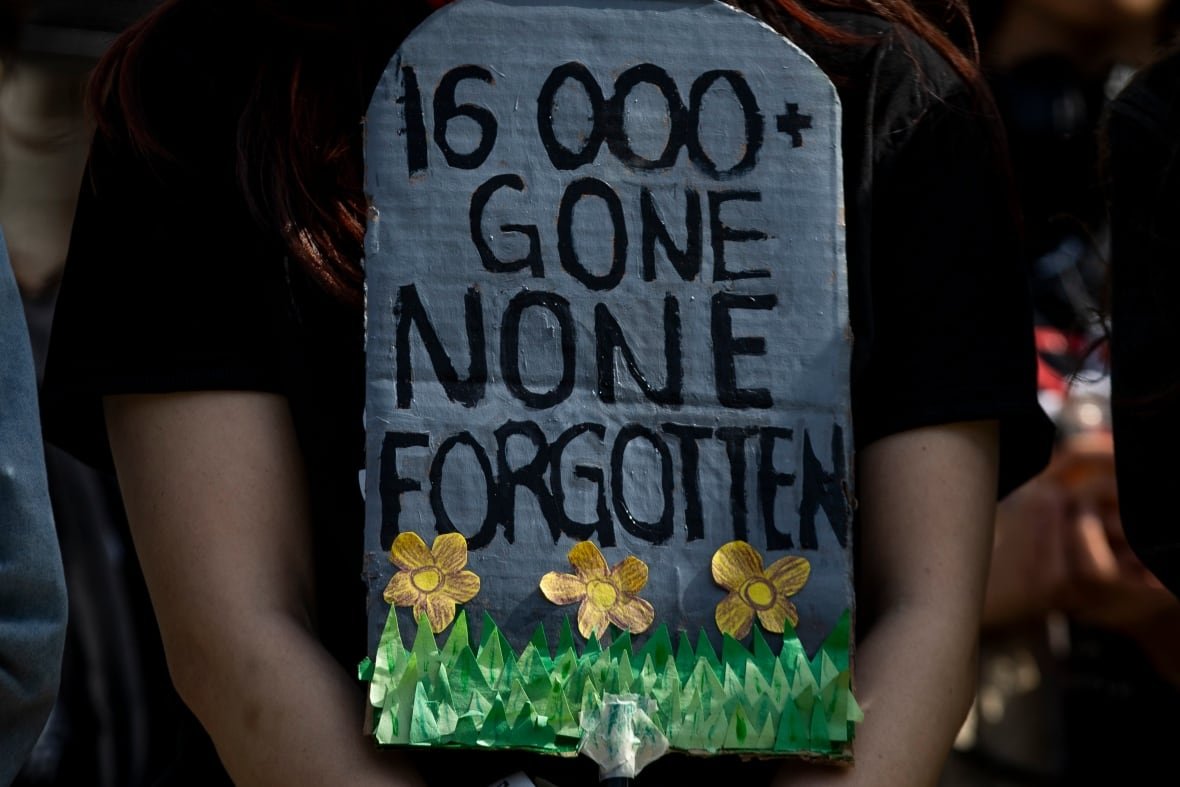 9th-anniversary-drug-crisis-3 A closeup of a sign held by a person that says, 16,000 done. None forgotten.