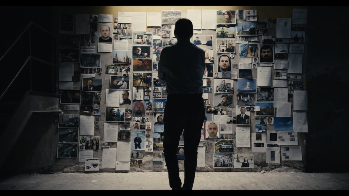antidote A man stands in front of a wall of photos.