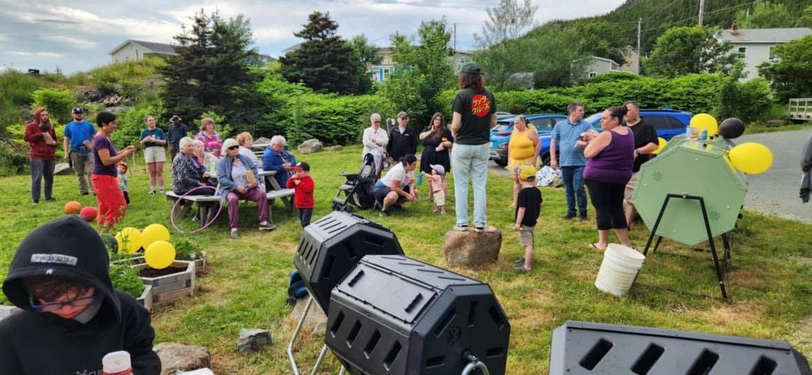 bauline-bee-garden-event Group of people sit and stand in a garden to kick off the Beauline composting program. There's some balloons and big compost bins.