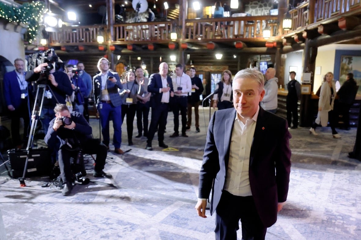 canada-politics-3 A man walks toward the camera, with a group of reporters behind.
