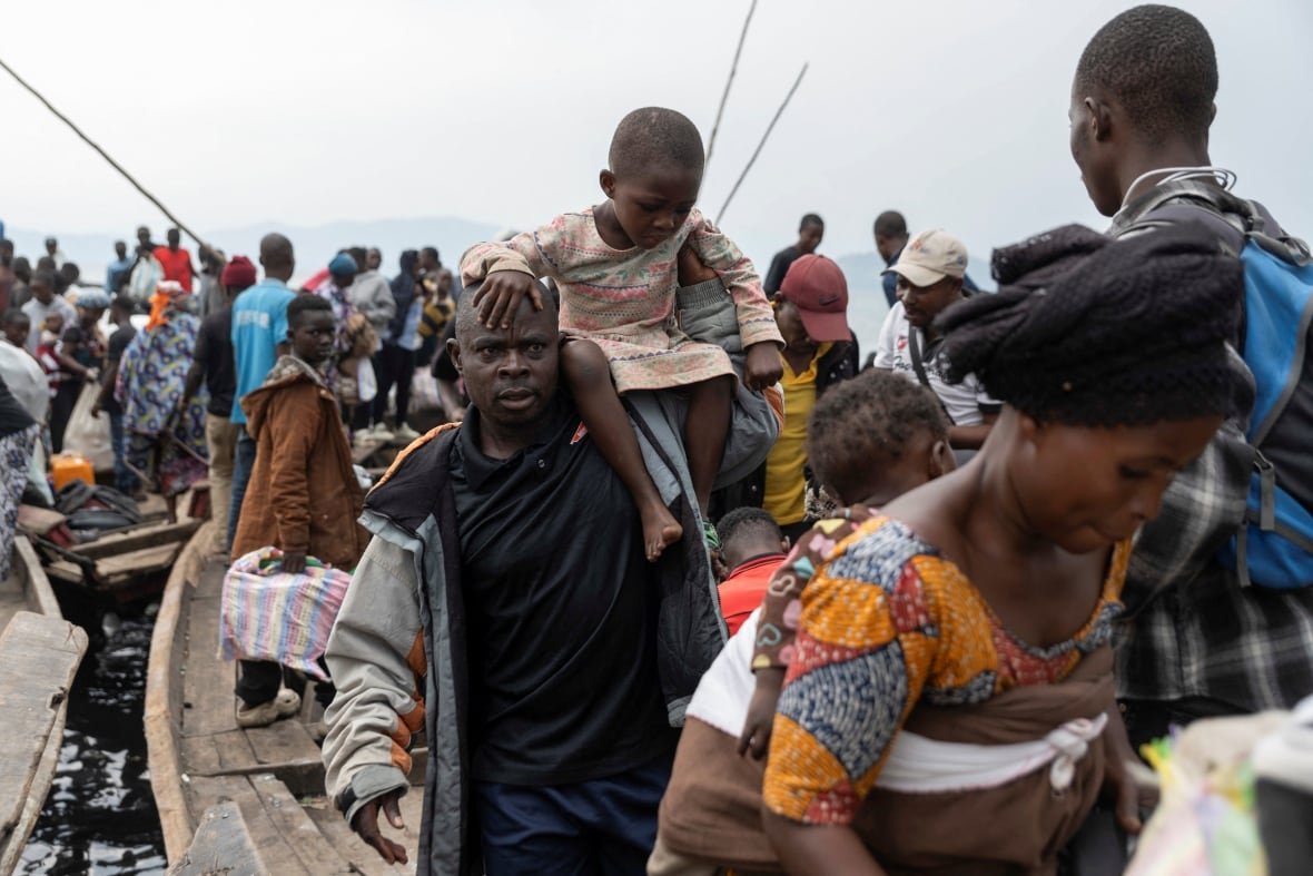 A large crowd of people arrives by boat.