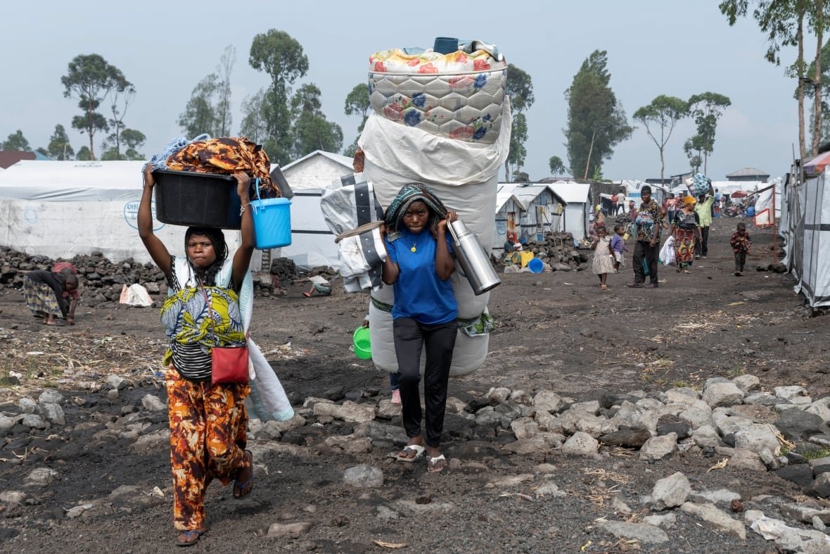 People carry their belongings as they walk.