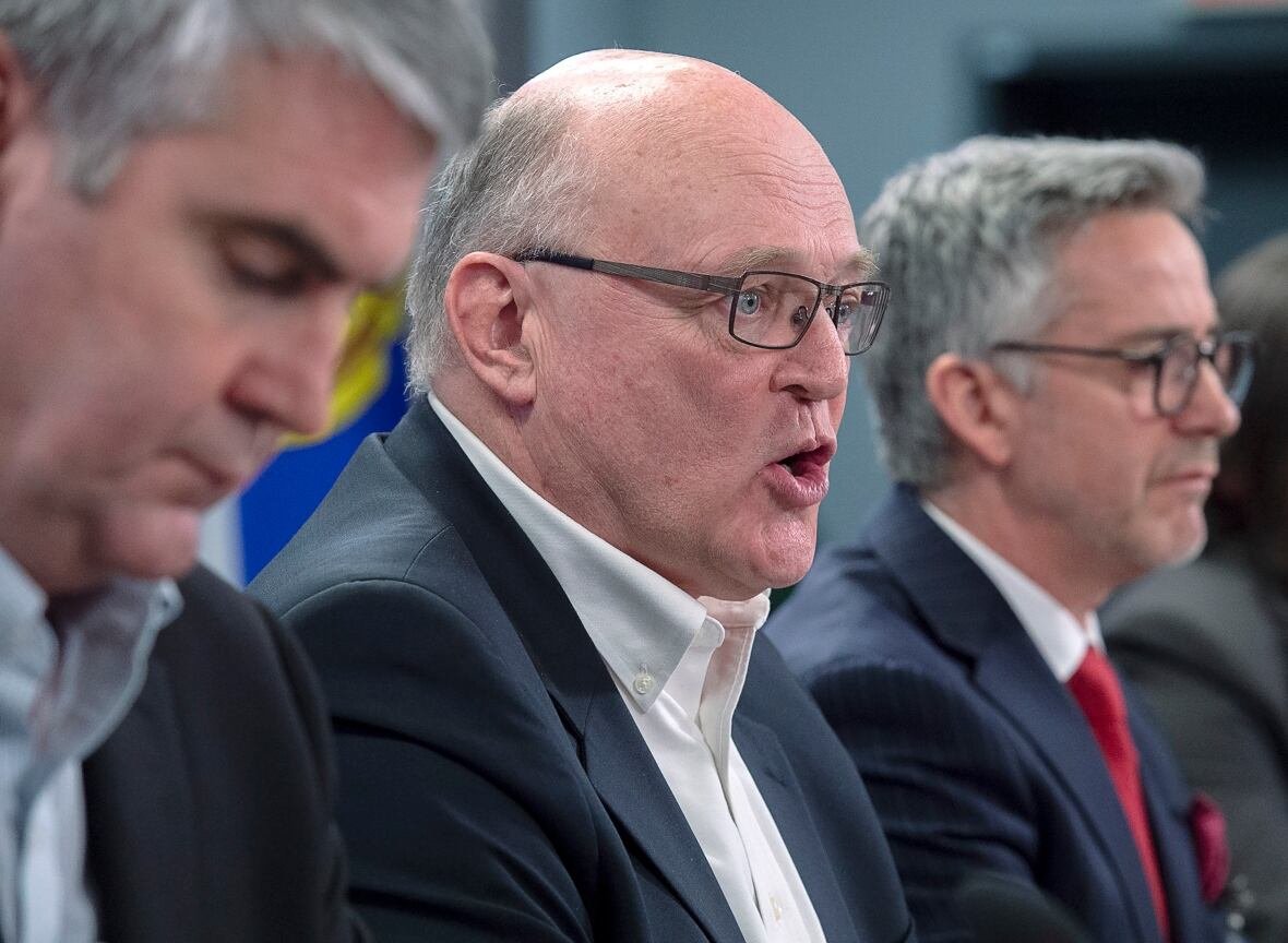 covid-atlantic-20200317 Three men sit close together during a press conference during the early days of the COVID-19 pandemic.