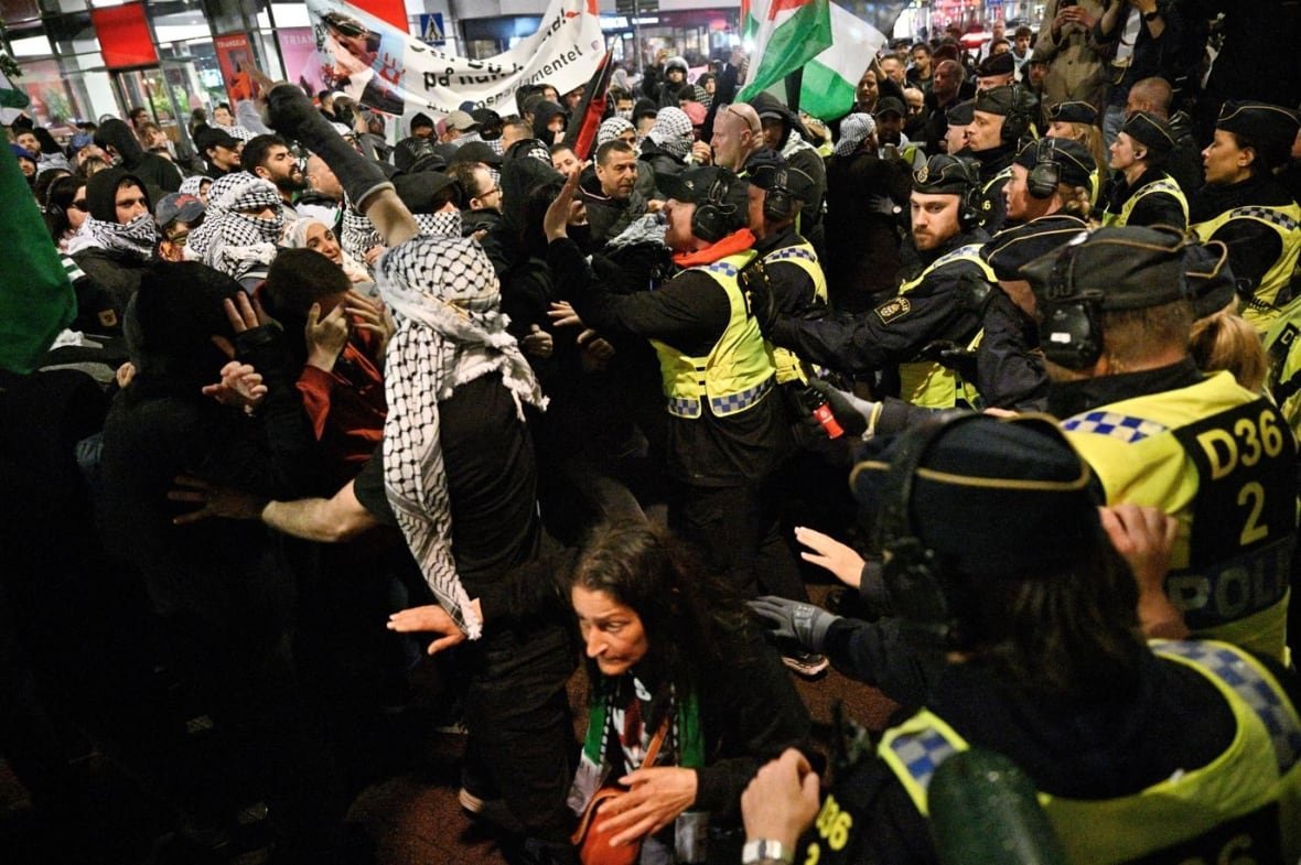 eurovision-protest Police on the right push back a crowd of protesters.