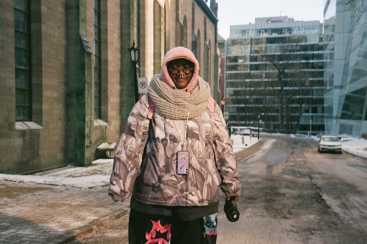 frankieb-lambert-1 A person dressed in colourful clothing stands in front of a church in winter.