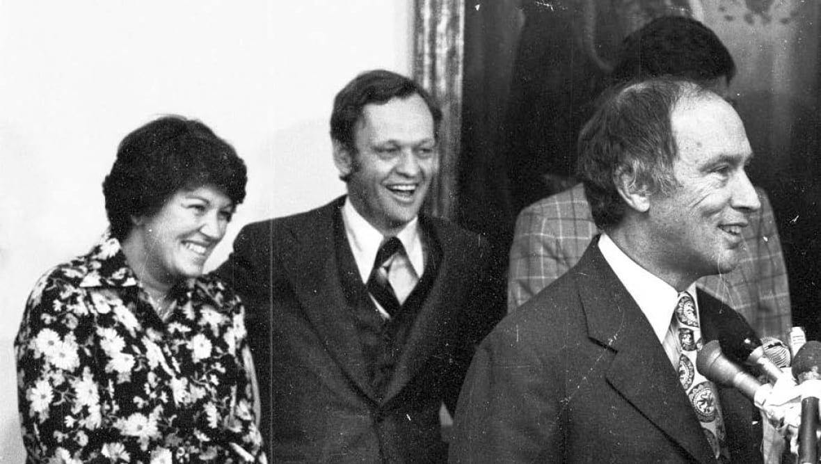 monique-begin-trudeau Bégin smiling in a vintage black and white photo behind then-prime minister Pierre Elliott Trudeau.