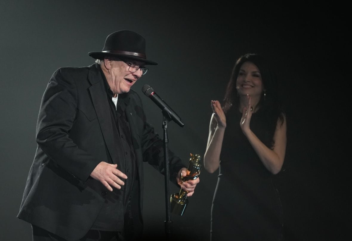 music-juno-awards-20250329-8 A person accepts an award on stage as another person claps.
