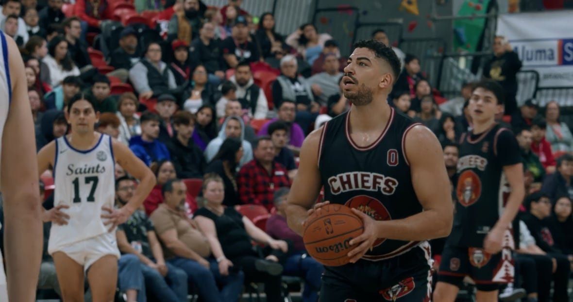 saints-and-warriors A man in a basketball uniform standing in front of a crowd. looks as if he is about to take a shot.