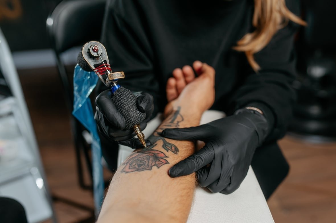 tattoo-artist A tattoo artist inks a rose on a man's forearm.