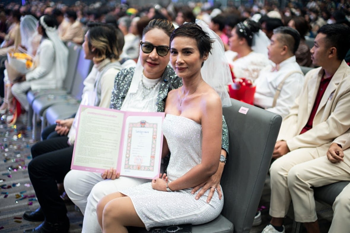 thailand-lgbtq A couple sits on chairs holding a certificate.