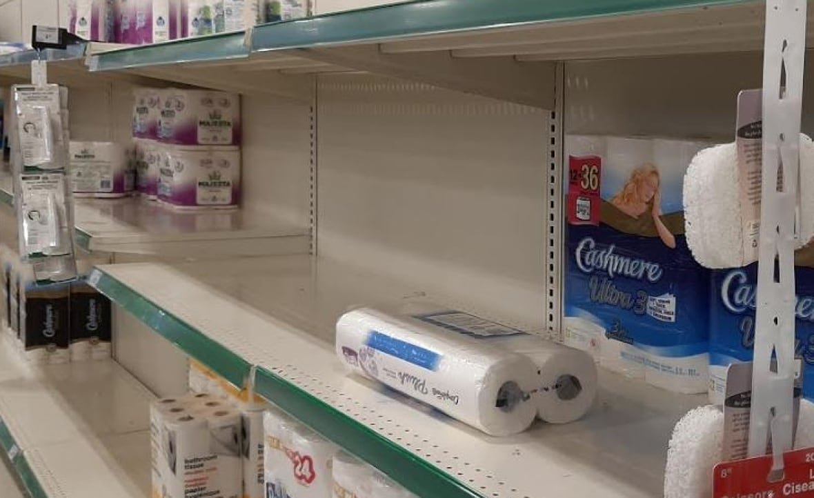 toilet-paper-covid-19 A grocery store shelf that is normally filled with paper towels and toilet paper is mostly empty.