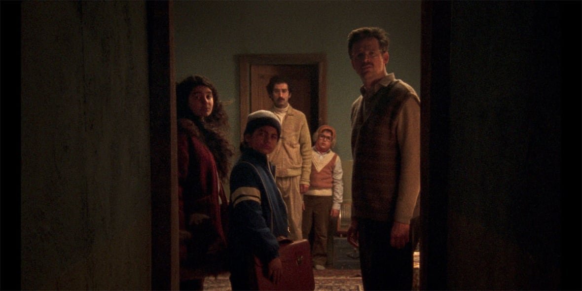 universal-language-matthew-rankin A still from a movie shows five people, two adults and three children, looking through a doorway.