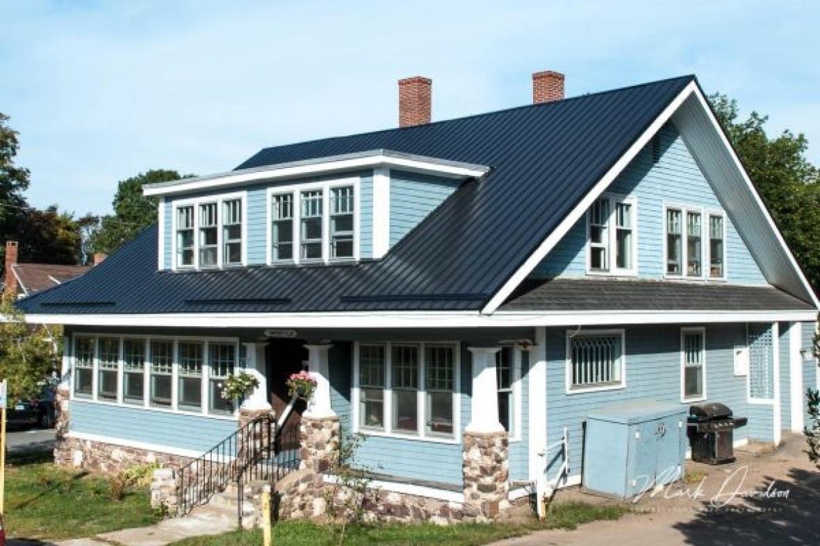 17-westwood-avenue-wolfville A blue house withtwo chimneys, a stone foundation and pillars.