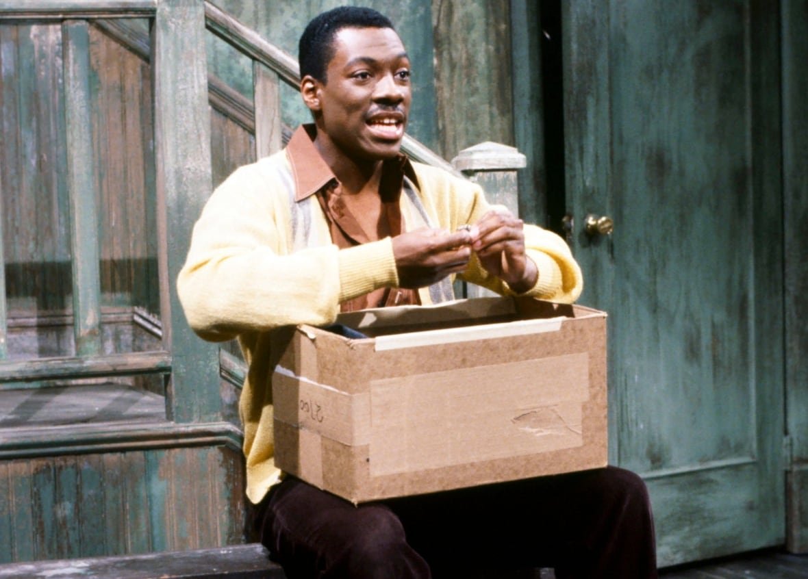 eddie-murphy Eddie Murphy sitting on the SNL stage.