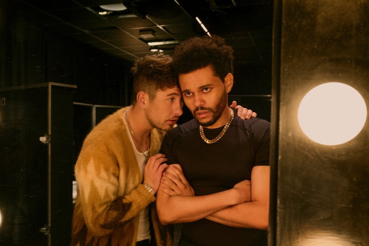 film-review-hurry-up-tomorrow-1 A man crosses his arms while looking into a mirror. Another man on his left leans on his shoulder and rests his head against his cheek.