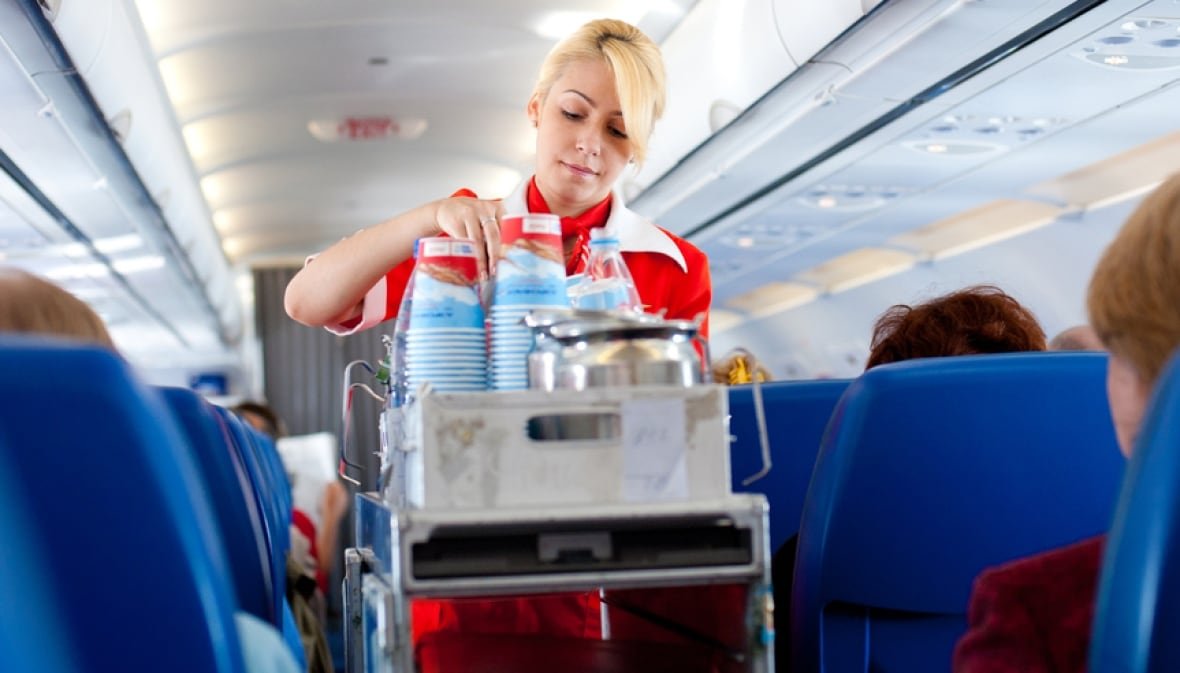 flight-attendant-plane-generic-trolley-cart-food Flight attendant with a food and drink trolley.