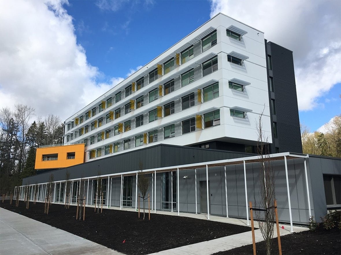 foxglove-housing A long low, white building with apartments in a row above the main level.