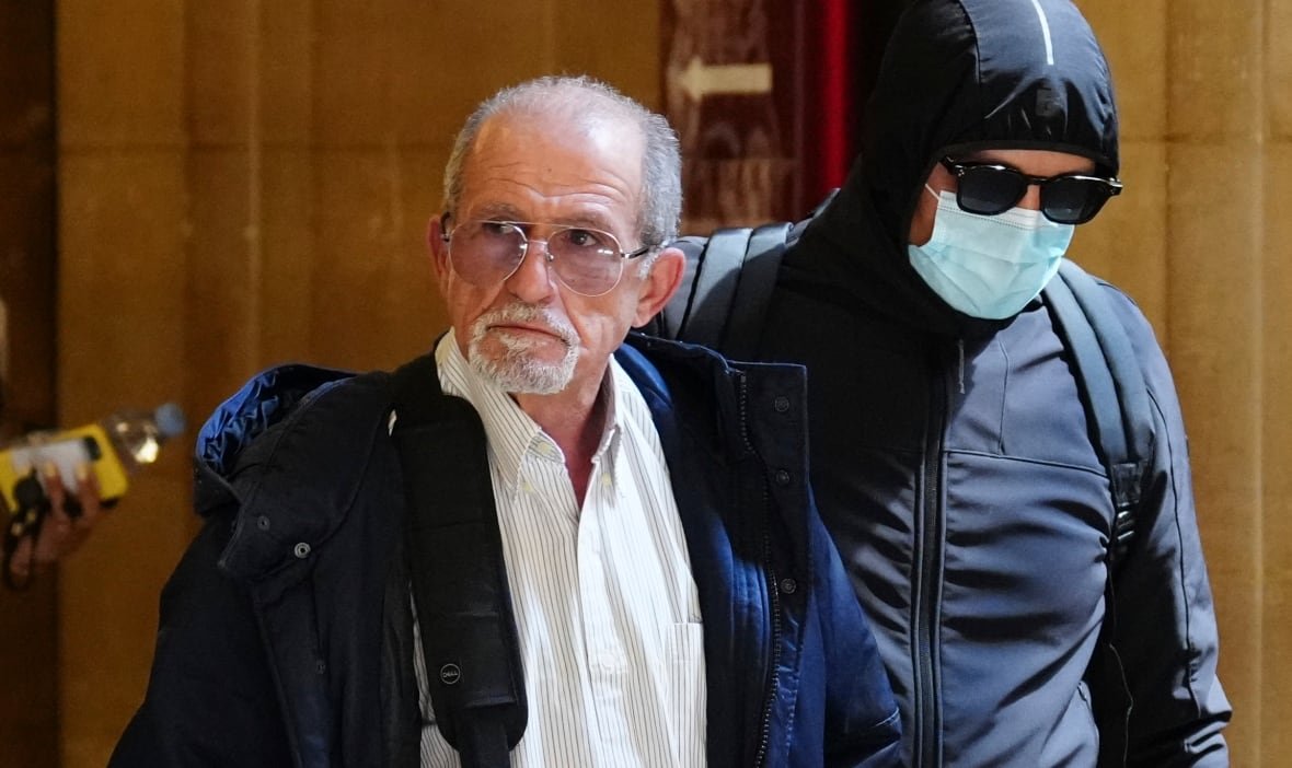 france-kardashian-robbery-trial-1 An older man with glasses and a goatee is on the left side of the image next to a taller man who is wearing a blue surgical mask and sunglasses.