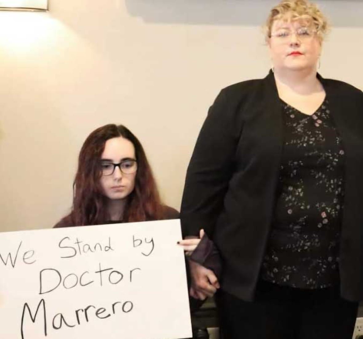gabrielle-cormier-and-stepmother-stacie-quigley-cormier-of-dalhousie-junction A young woman in a wheelchair holding a sign that reads, 'We stand by Doctor Marrero,' beside an older woman.