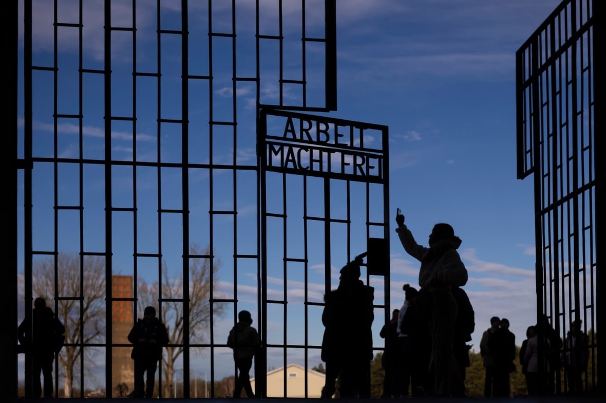 germany-auschwitz-80th-anniversary Silhouettes of people standing by a gate