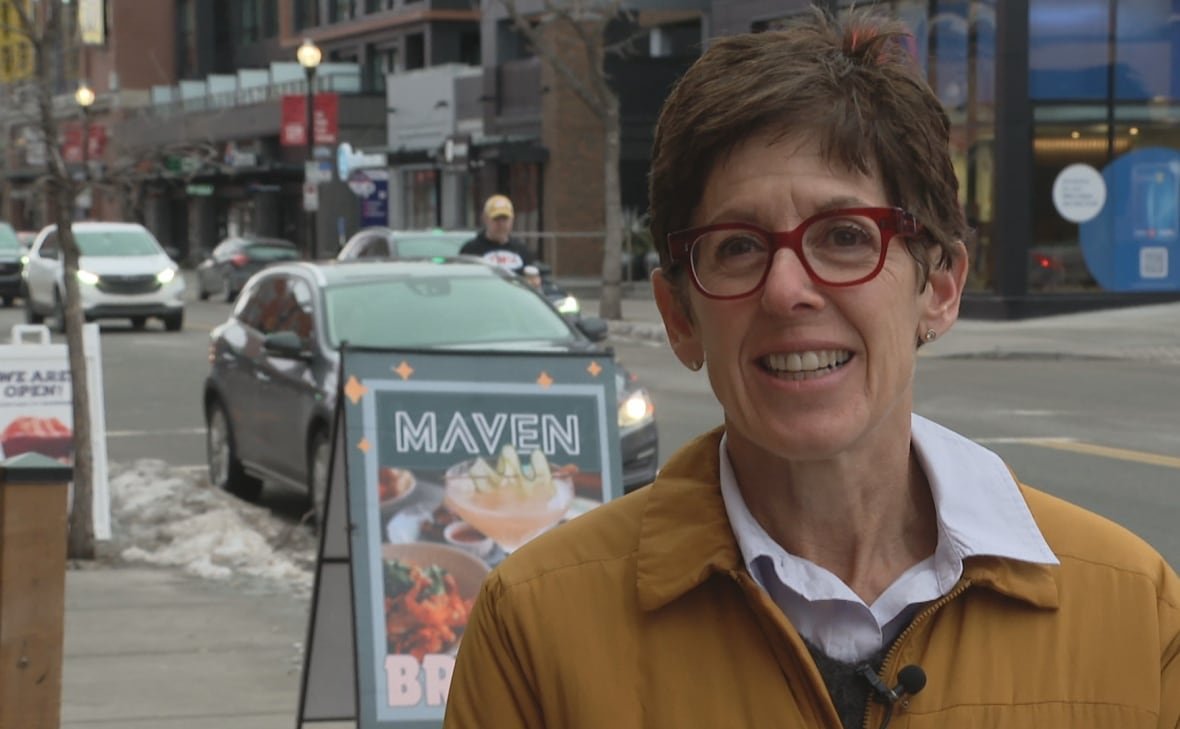 gst-yedlin A woman stands on a sidewalk talking to a reporter.