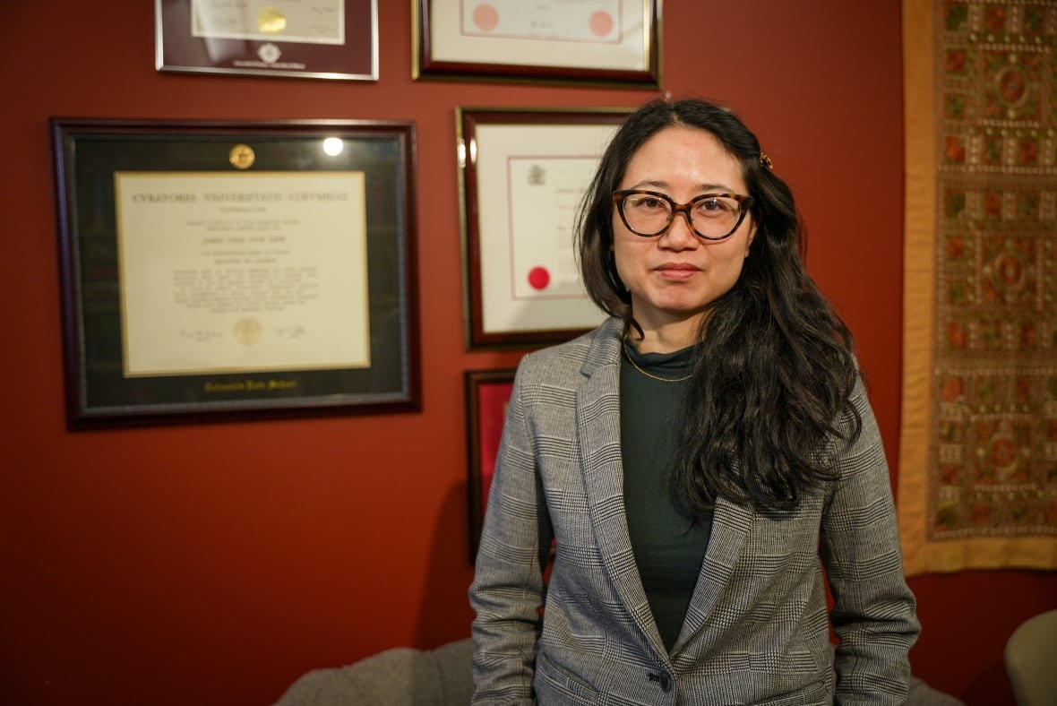 jamie-liew a woman standing against a wall in her office.