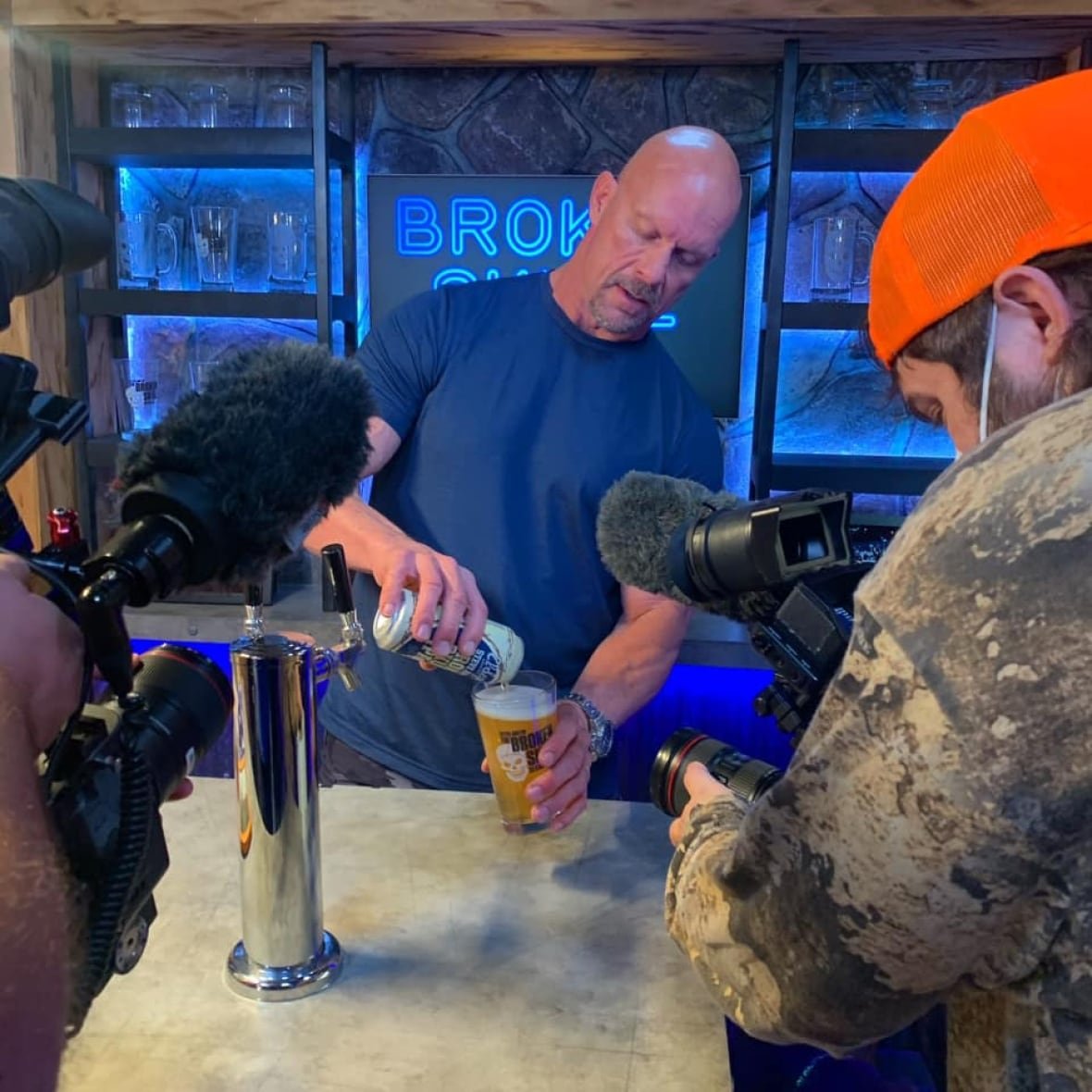 jason-eisener-stone-cold-steve-austin Wrestler (Stone Cold) Steve Austin is shown pouring a beer, while a filmmaker wearing a red hat films him.
