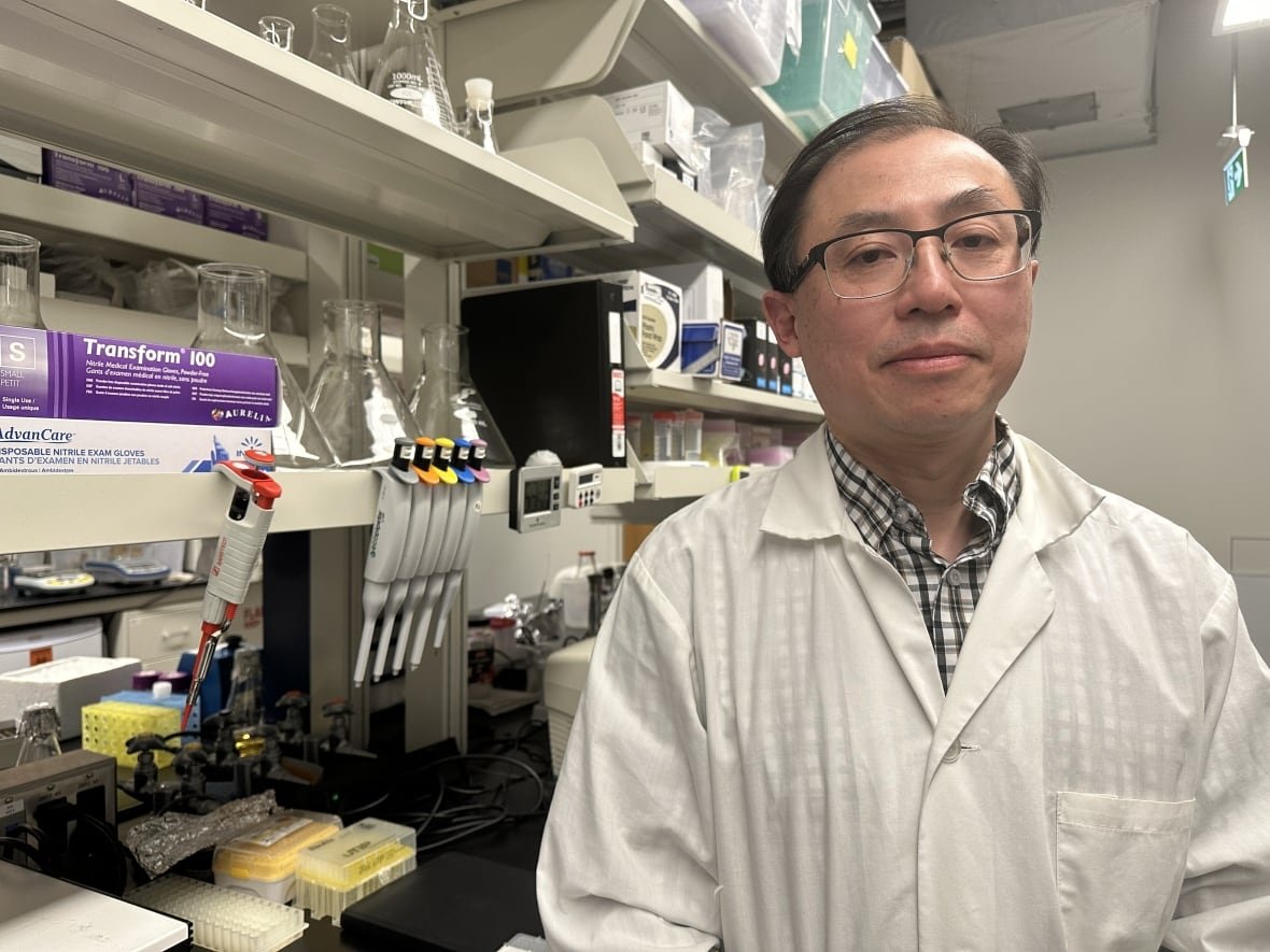 kenneth-ng A man stands in a white lab coat inside of a lab.