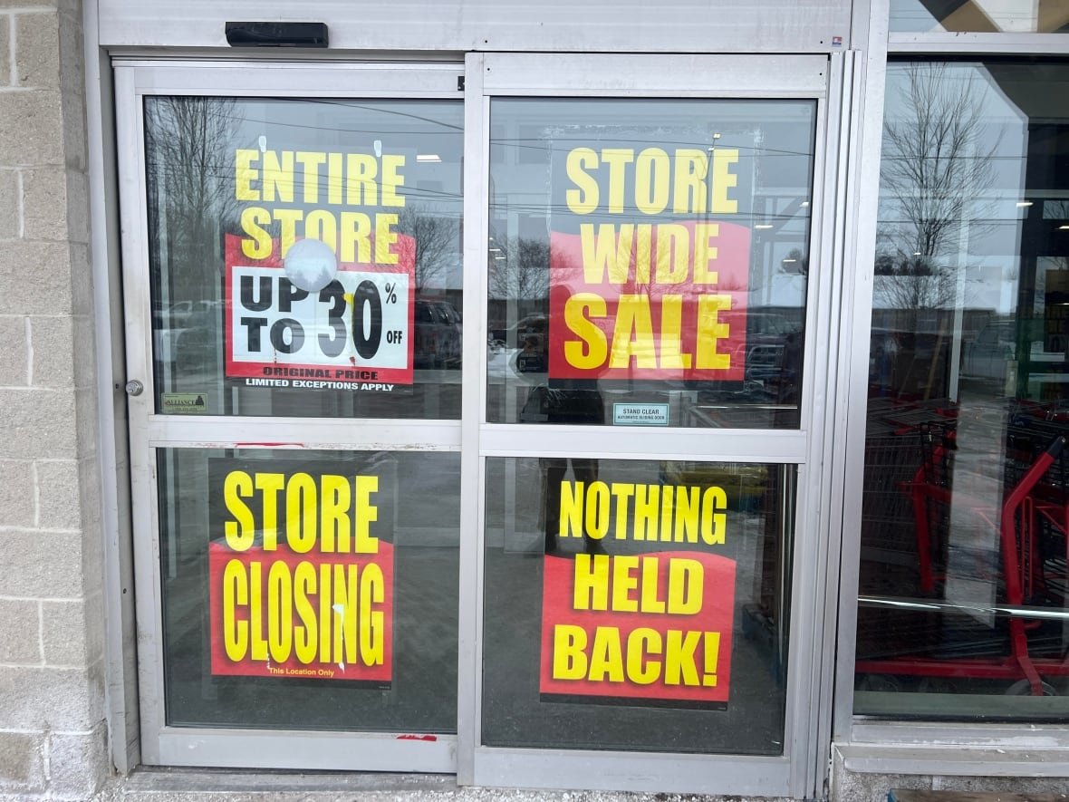 store-wide-sale-peavey-mart Signs on a storefront read 'Entire store up to 30% Store wide sale Store closing Nothing Held Back!'