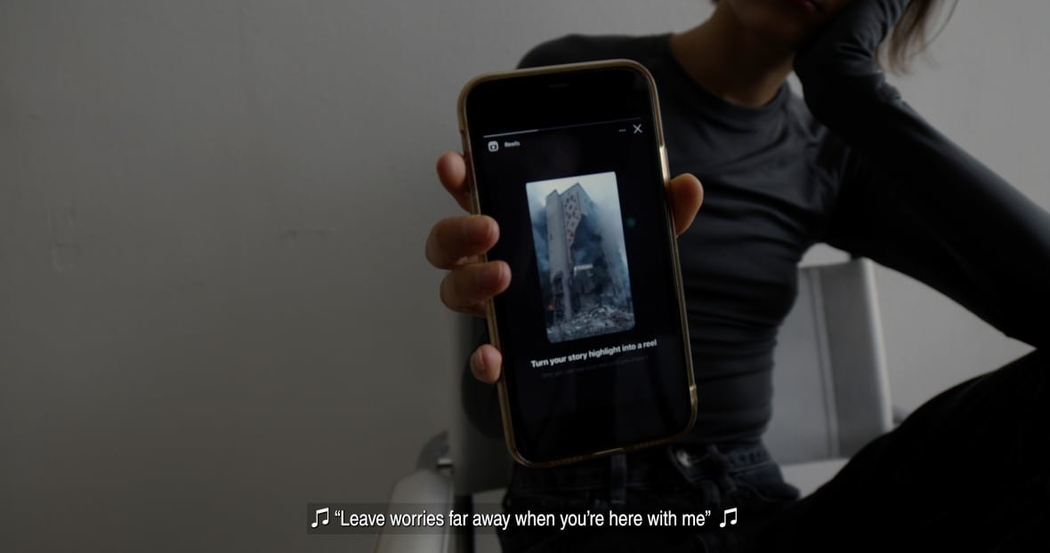 the-longer-you-bleed A woman holds up a phone to the camera. On it, a blown-up building is shown. Underneath photo of the building are the words 'Turn your story highlight into a reel.'