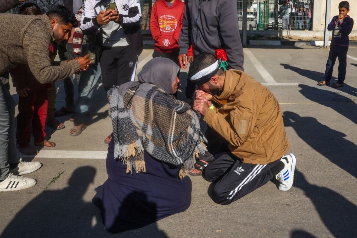 Two people hold hands as they kneel on the ground.