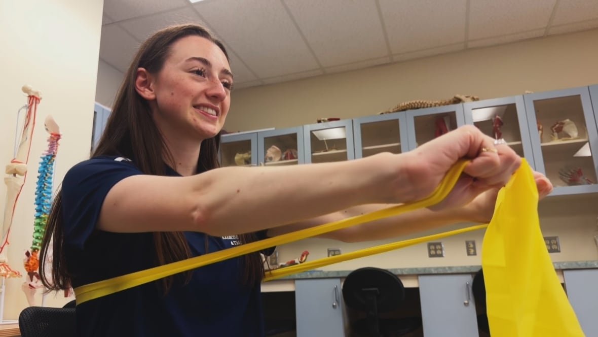 amanda-daniels-1 A woman pulls an elastic band to stretch her arms.